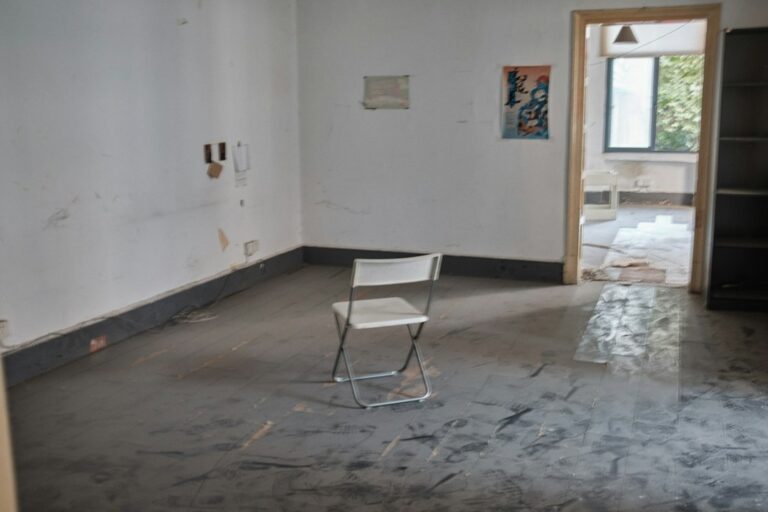 Homeowner rolling epoxy coating across a prepared concrete garage floor with tools and protective gear nearby